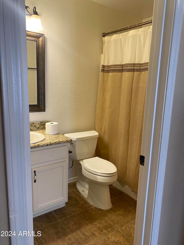 bathroom with toilet, vanity, and tile patterned floors