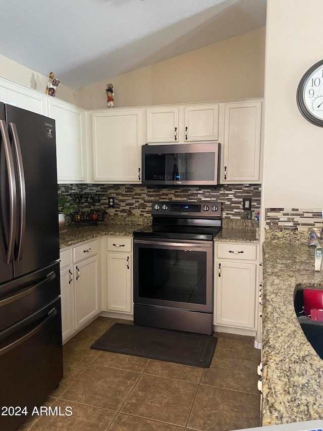 kitchen featuring tasteful backsplash, vaulted ceiling, dark tile patterned flooring, and stainless steel appliances