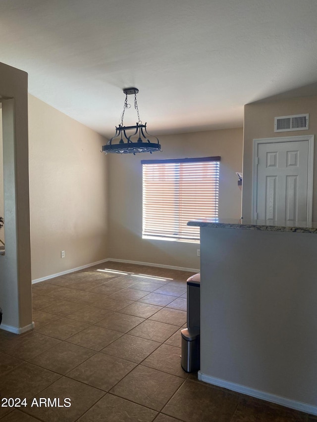 tiled spare room featuring a notable chandelier