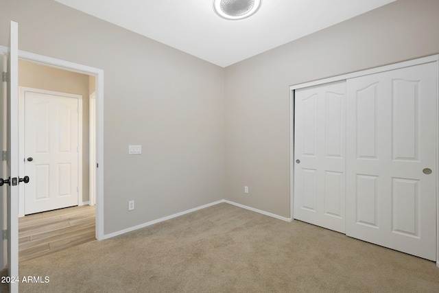 unfurnished bedroom featuring light colored carpet and a closet