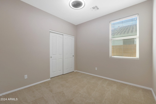 unfurnished bedroom featuring light carpet and a closet