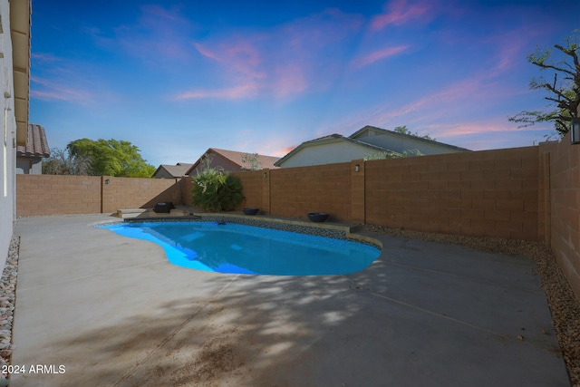 pool at dusk featuring a patio