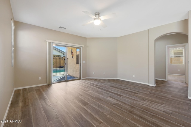 empty room with a wealth of natural light, dark hardwood / wood-style flooring, and ceiling fan