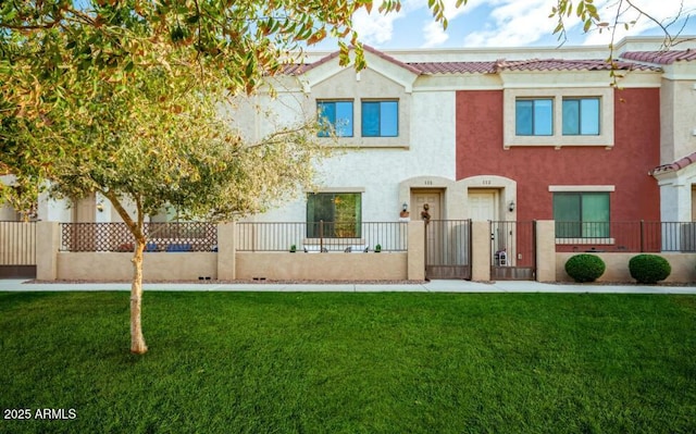 view of front of property featuring a fenced front yard, a tiled roof, a front lawn, and stucco siding