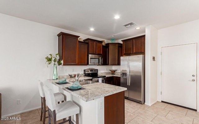 kitchen with a peninsula, visible vents, a kitchen breakfast bar, light countertops, and appliances with stainless steel finishes