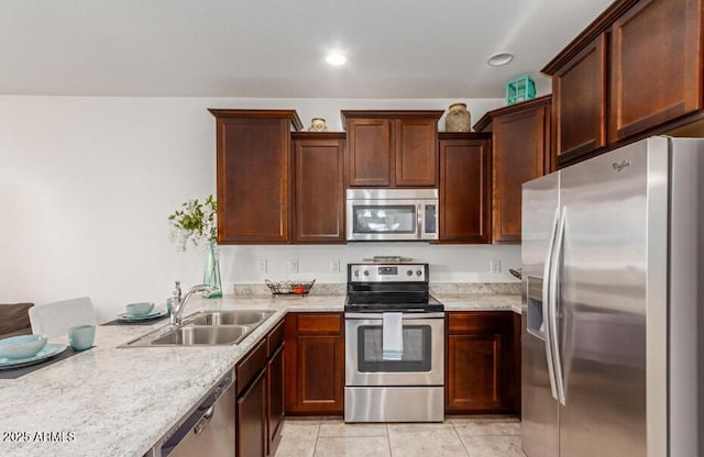 kitchen with light tile patterned floors, recessed lighting, a peninsula, a sink, and appliances with stainless steel finishes