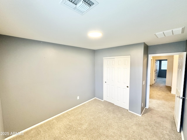 unfurnished bedroom featuring visible vents, light carpet, and baseboards