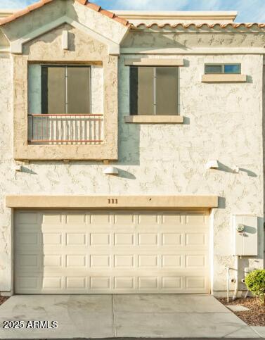 view of front of house featuring a garage, a balcony, and stucco siding