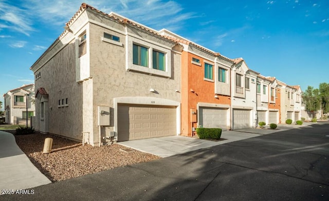 view of building exterior featuring an attached garage, driveway, and a residential view