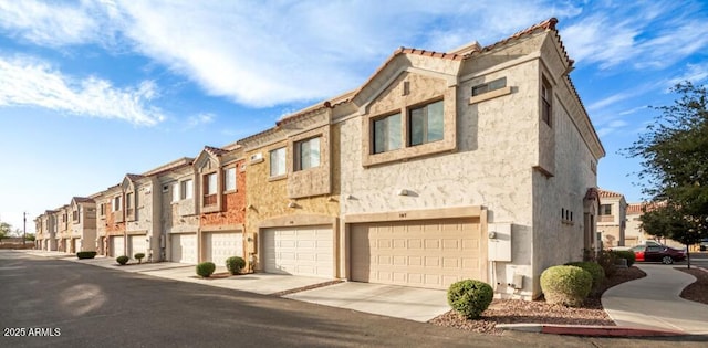 view of building exterior with driveway, an attached garage, and a residential view