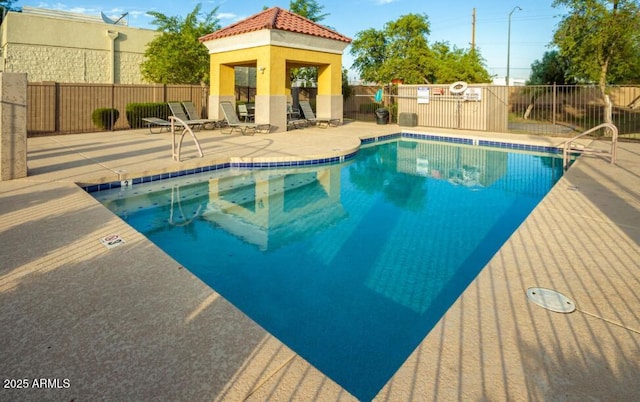 community pool with a gazebo, a patio, and fence