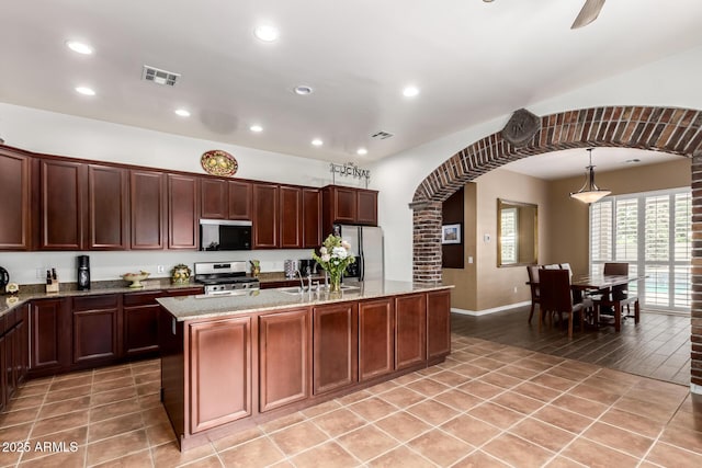 3441 S Halsted Pl, Chandler, AZ 85286 - kitchen featuring stainless steel appliances, arched walkways, recessed lighting, light stone countertops, and an island with sink