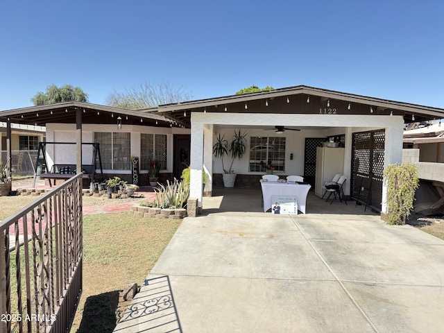 rear view of property featuring a ceiling fan and fence