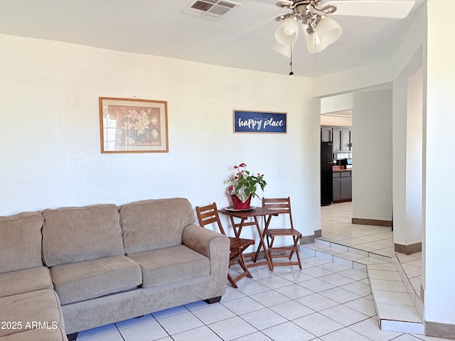 living room with light tile patterned floors, visible vents, baseboards, and a ceiling fan