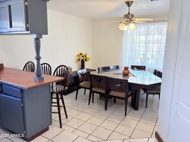 dining space featuring light tile patterned flooring, a ceiling fan, and a textured ceiling