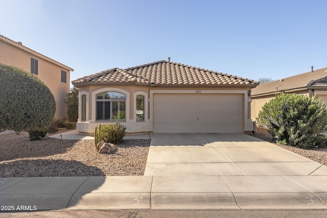 mediterranean / spanish-style home with a garage, concrete driveway, a tiled roof, and stucco siding