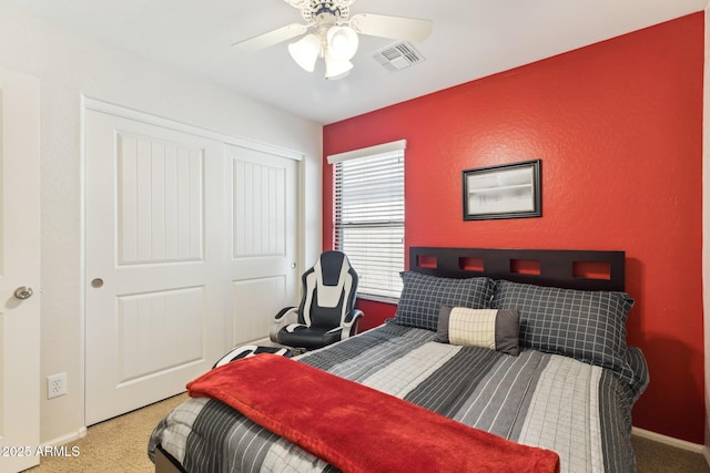 carpeted bedroom with a ceiling fan, a closet, visible vents, and baseboards