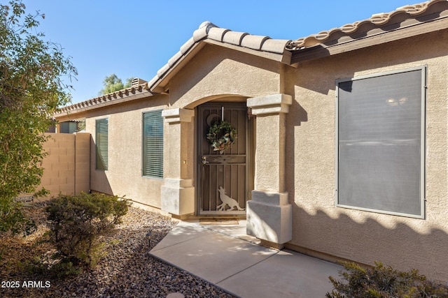 entrance to property featuring fence and stucco siding