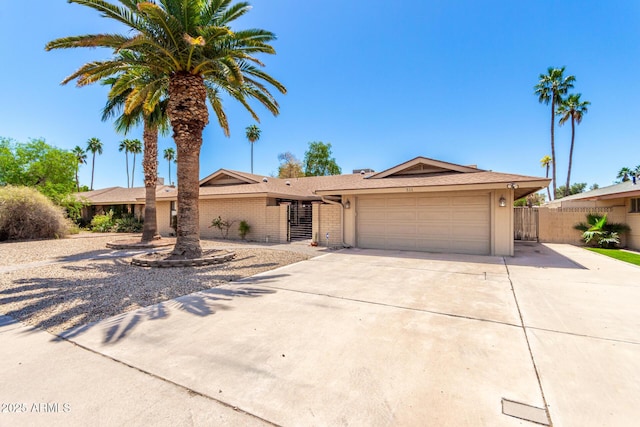 single story home featuring brick siding, driveway, a garage, and fence