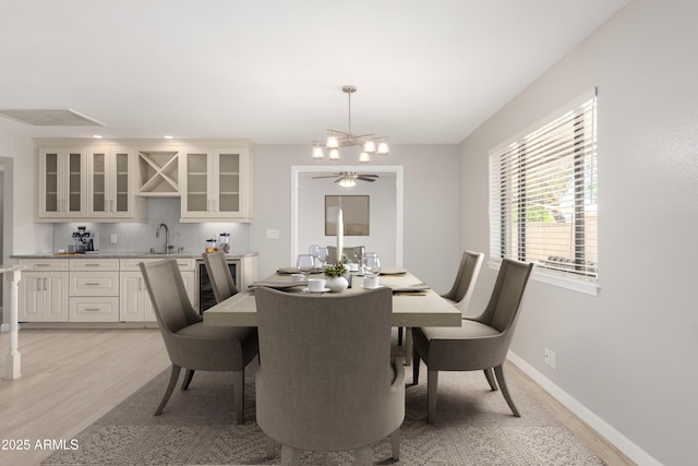 dining space featuring indoor wet bar, a chandelier, recessed lighting, and light wood-style flooring