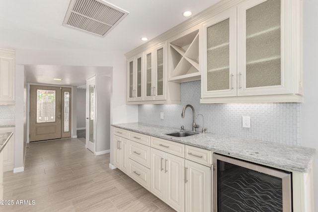 kitchen with a sink, wine cooler, visible vents, and backsplash
