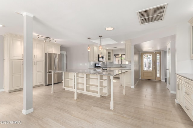 kitchen featuring stainless steel appliances, a kitchen island, a sink, visible vents, and a kitchen breakfast bar