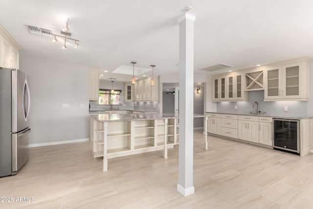 kitchen with baseboards, beverage cooler, decorative backsplash, and freestanding refrigerator