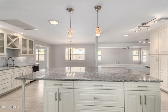 kitchen featuring a ceiling fan, a healthy amount of sunlight, glass insert cabinets, and a sink