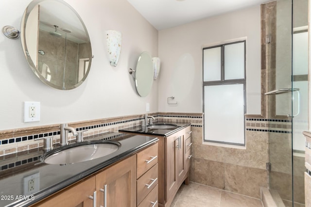 full bath with tile walls, a sink, a shower stall, and double vanity