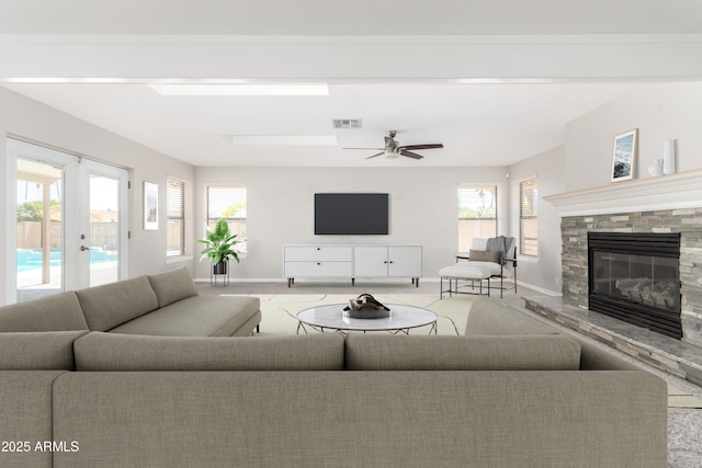 carpeted living room with a fireplace, visible vents, a wealth of natural light, and baseboards