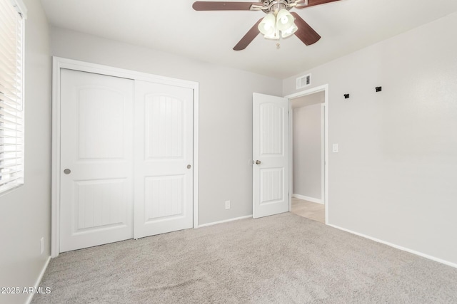 unfurnished bedroom featuring carpet flooring, a closet, a ceiling fan, visible vents, and baseboards