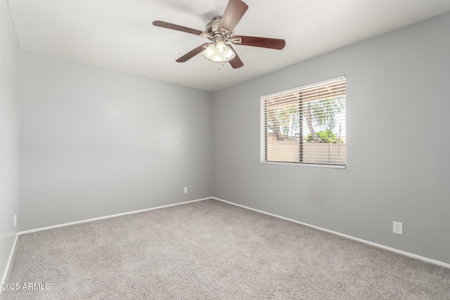 carpeted spare room with a ceiling fan and baseboards