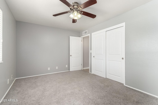 unfurnished bedroom featuring carpet flooring, a closet, a ceiling fan, visible vents, and baseboards