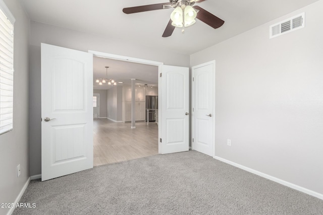 unfurnished bedroom with baseboards, visible vents, multiple windows, and carpet