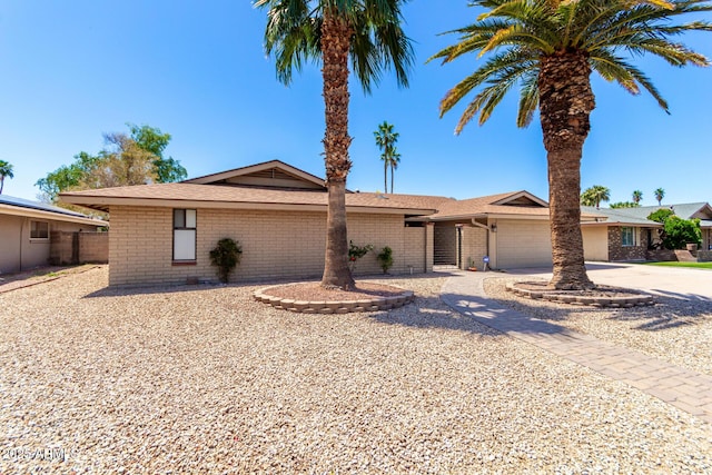 single story home with driveway, an attached garage, and brick siding
