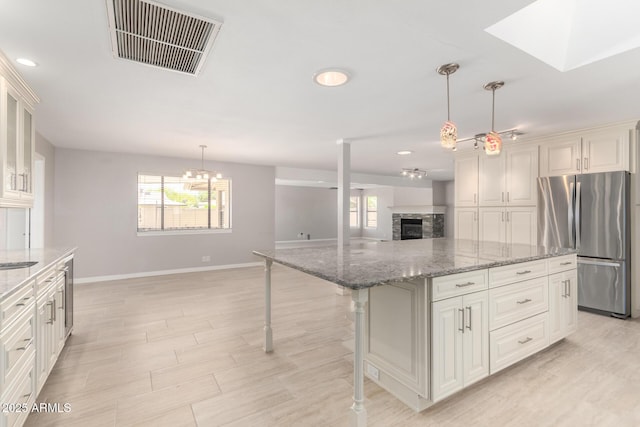 kitchen featuring plenty of natural light, visible vents, freestanding refrigerator, and baseboards