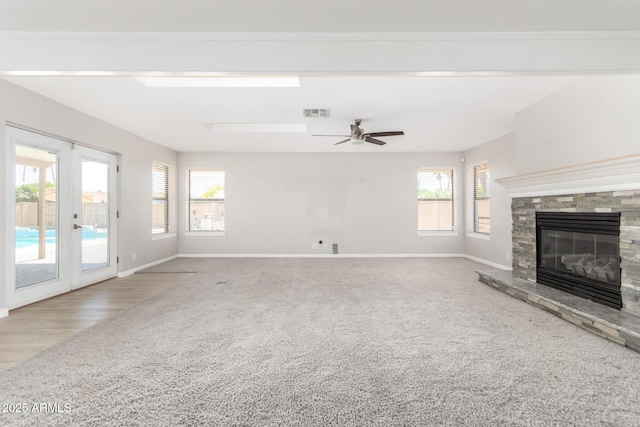 unfurnished living room with baseboards, a fireplace, carpet flooring, and plenty of natural light