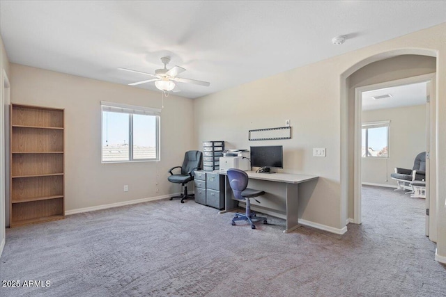 office space featuring a wealth of natural light, light carpet, and ceiling fan