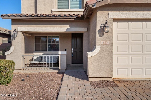 view of exterior entry with a garage and a porch