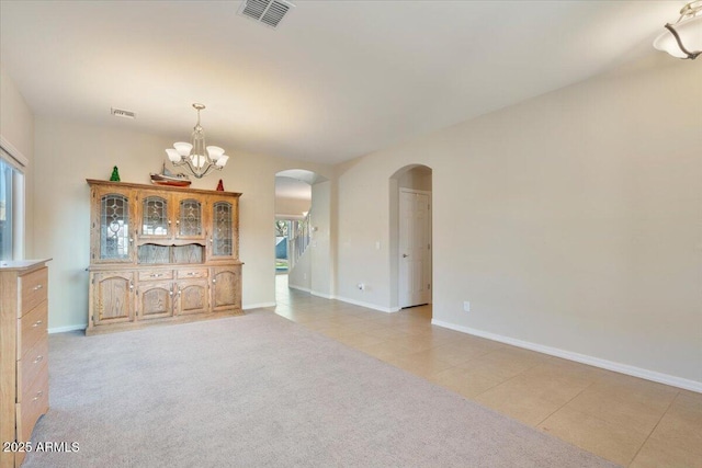 unfurnished living room featuring light carpet and a notable chandelier