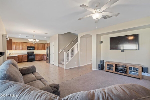 living room with ceiling fan with notable chandelier, sink, and light tile patterned floors