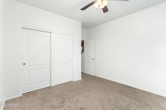 unfurnished bedroom featuring light carpet, ceiling fan, and a closet