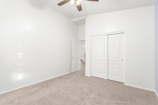 unfurnished bedroom featuring ceiling fan, light carpet, a closet, and vaulted ceiling