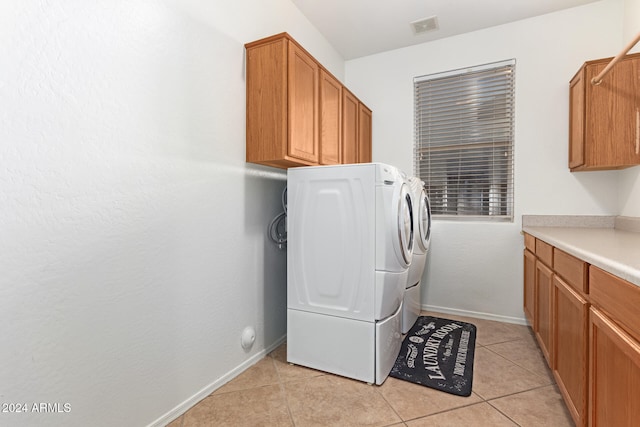 laundry area featuring washing machine and dryer, cabinets, and light tile patterned floors