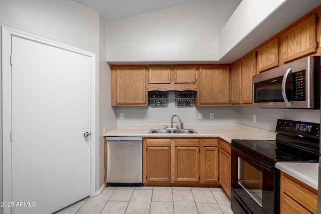 kitchen featuring brown cabinetry, stainless steel appliances, a sink, and light countertops