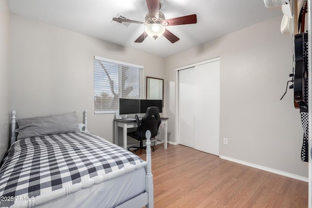 bedroom featuring light wood-style floors, ceiling fan, baseboards, and a closet