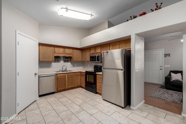 kitchen featuring ceiling fan, appliances with stainless steel finishes, brown cabinets, light countertops, and a sink