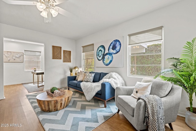 living area with baseboards, ceiling fan, and wood finished floors