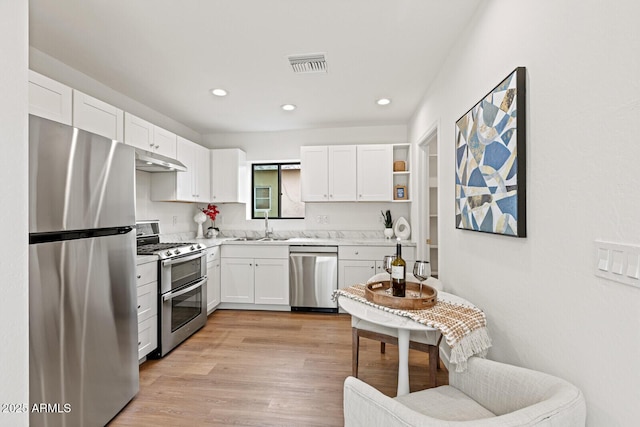 kitchen with visible vents, under cabinet range hood, appliances with stainless steel finishes, white cabinets, and a sink