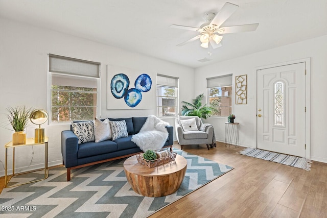 living area with visible vents, baseboards, wood finished floors, and a ceiling fan